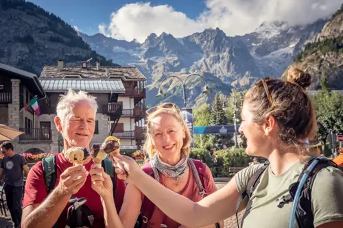 A group of three travelers sharing a sweet treat outdoors